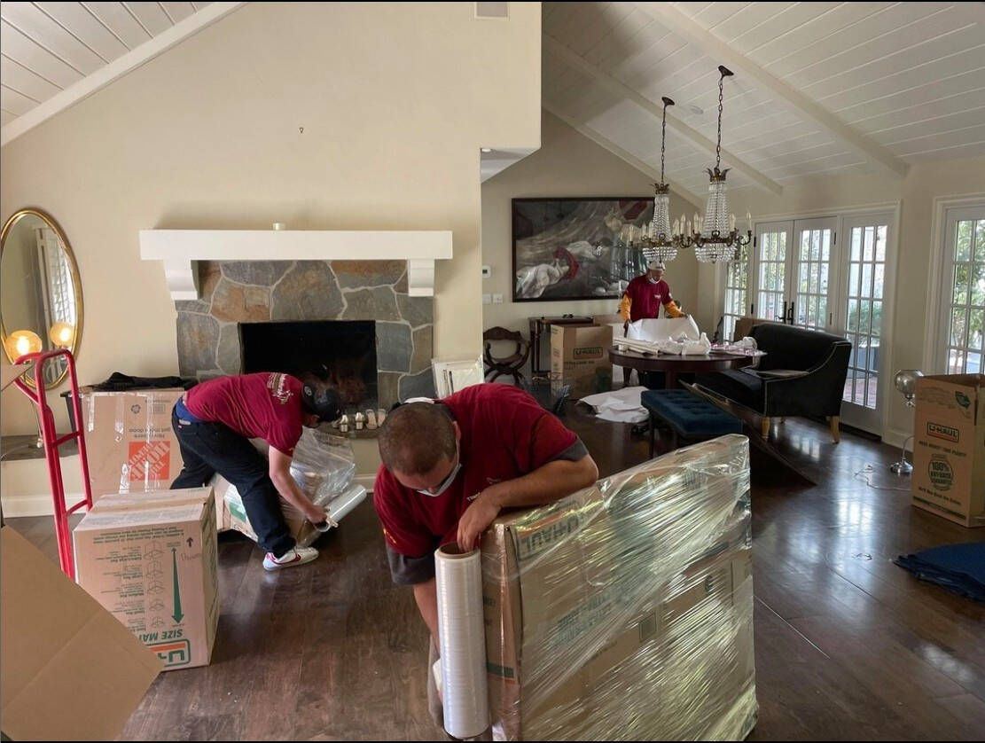 Movers wrapping furniture with moving pads.