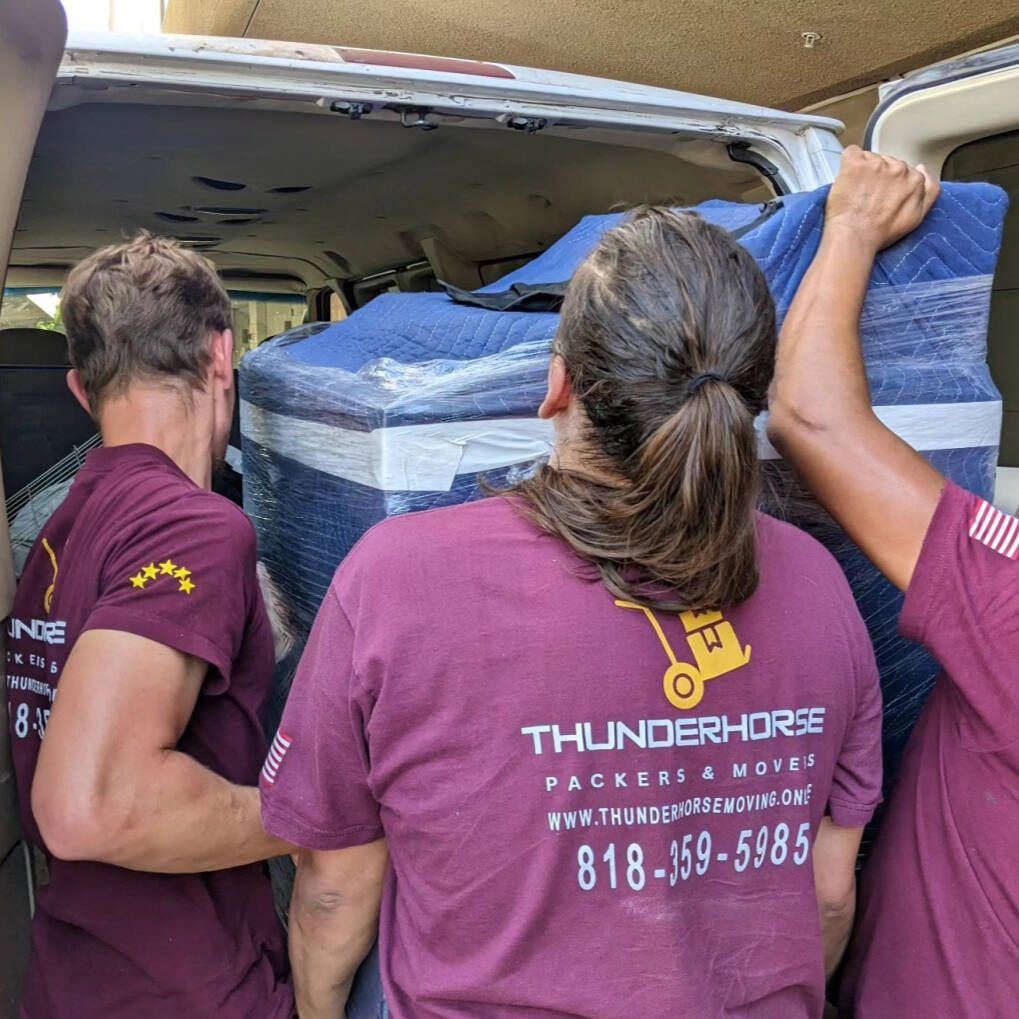 Thunderhorse moving help team loading padded furniture into a rental truck