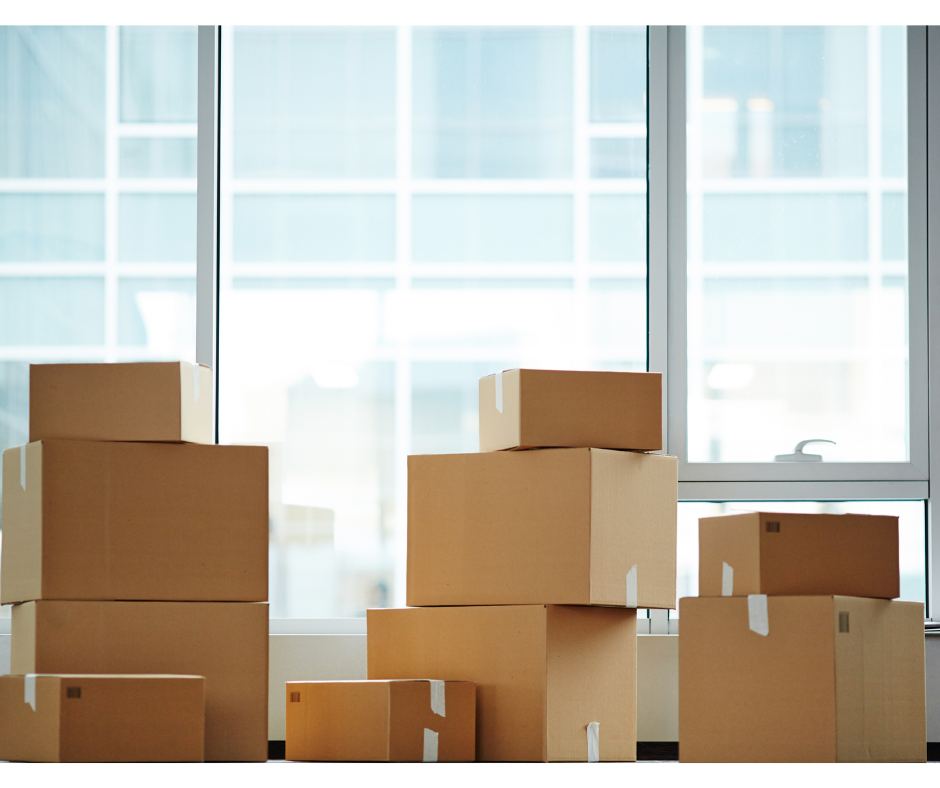 Stacked moving boxes and packing supplies by a window